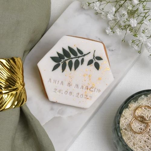 Ciasteczko maślane obłożone białym lukrem z wylukrowanymi liśćmi.