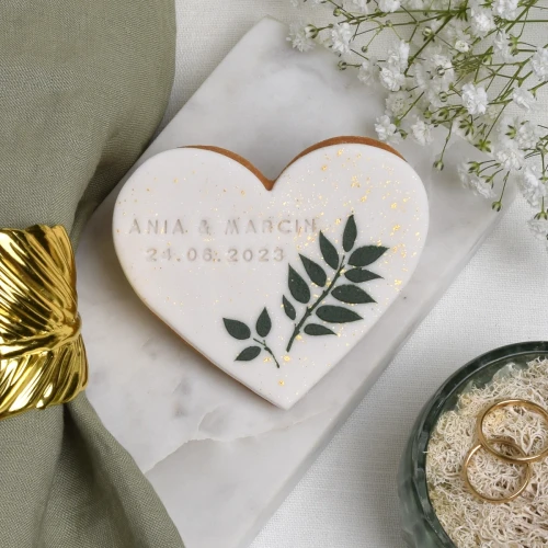 Maślane ciasteczko obłożone białym lukrem i zdobione lukrowanymi listkami