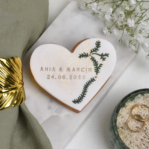 Maślane ciasteczko z białym lukrem, ozdobione lukrowanymi zielonymi listkami.