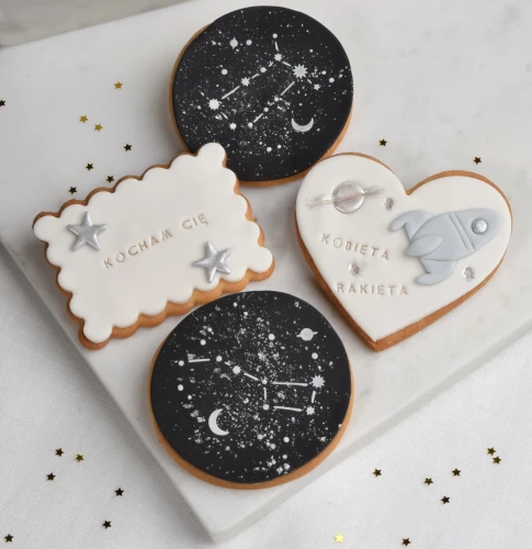 Zestaw ciasteczek maślanych, ozdobionych lukrem z motywami kosmosu i śmiesznym tekstem "Kobieta Rakieta".