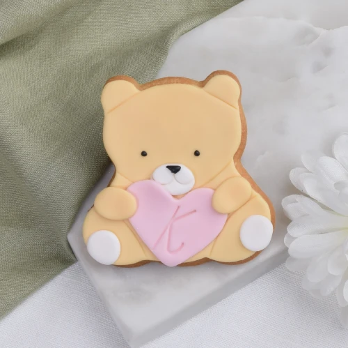 Ciasteczko lukrowane w kształcie misia trzymającego w łapkach serduszko.