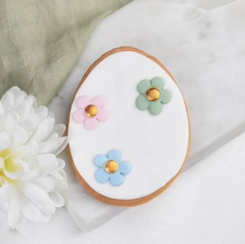 Wielkanocne ciasteczko w kształcie pisanki przyozdobione kolorowymi, lukrowanymi kwiatkami.