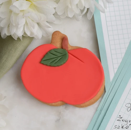 Ciasteczko lukrowane w kształcie czerwonego jabłuszka.
