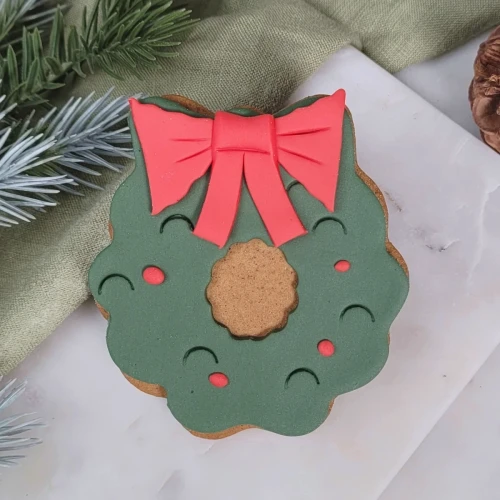 Ciasteczko lukrowane w kształcie Wieniec adwentowy z piękną, czerwoną kokardą.