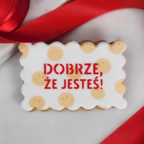 Ciasteczko z uśmiechniętymi buźkami i napisem "Dobrze, że jesteś"